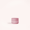 A small pink jar labeled Solawave Light Therapy Boosting Eye Cream, designed to reduce puffiness, rests on a minimalist surface with a soft shadow, while the plain pale background highlights the product.