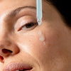 An image of a woman applying face serum to her face || 100mL