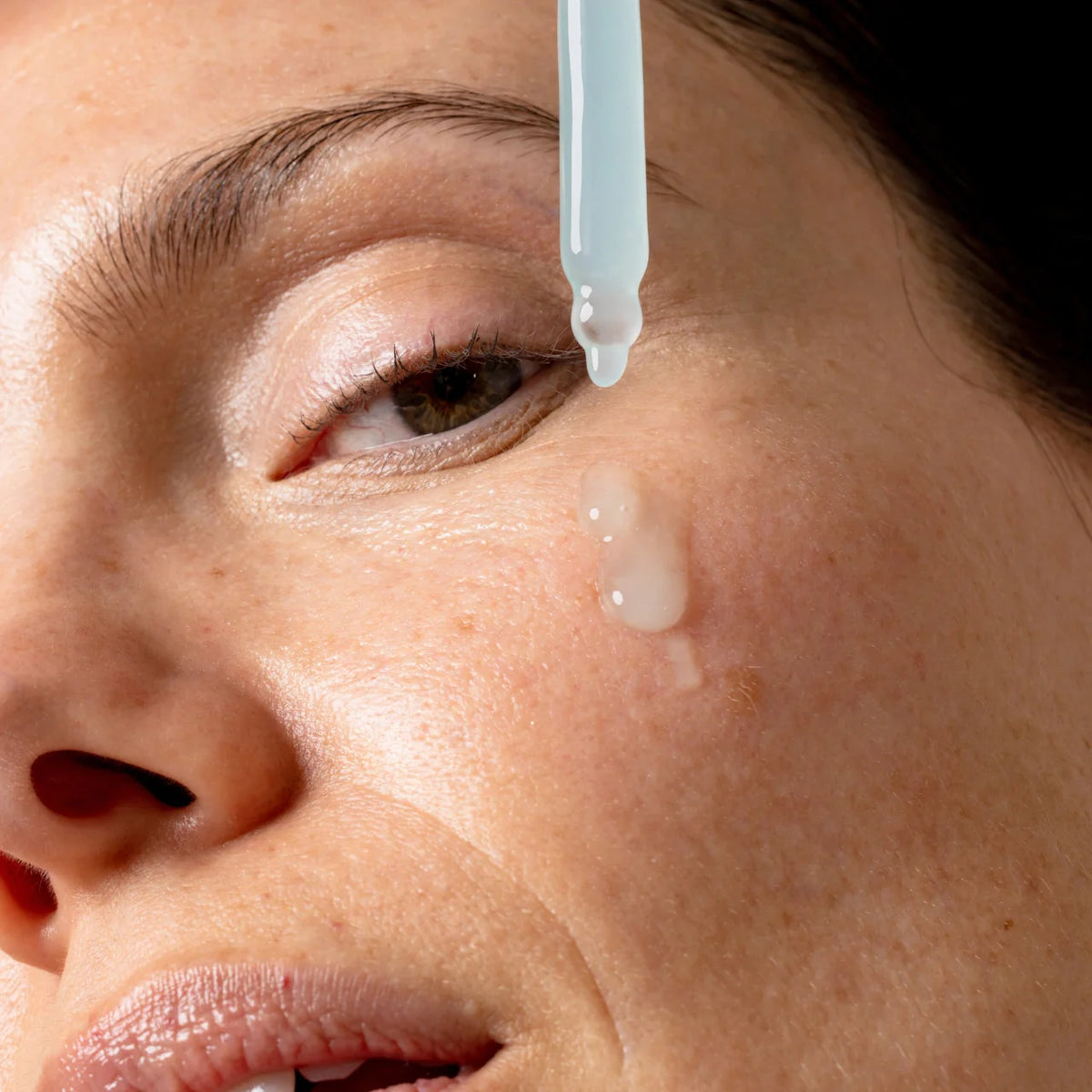 An image of a woman applying face serum to her face || 100mL