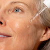An image of a woman applying facial serum