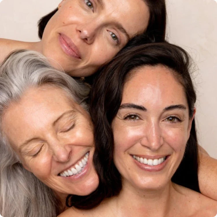 Three women smiling and embracing joyfully.