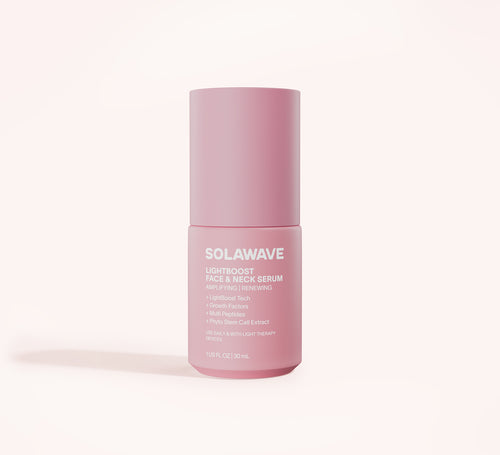A pink bottle labeled Solawave Light Therapy Boosting Face & Neck Serum stands upright on a light background, with product details and features printed in white text on the front.