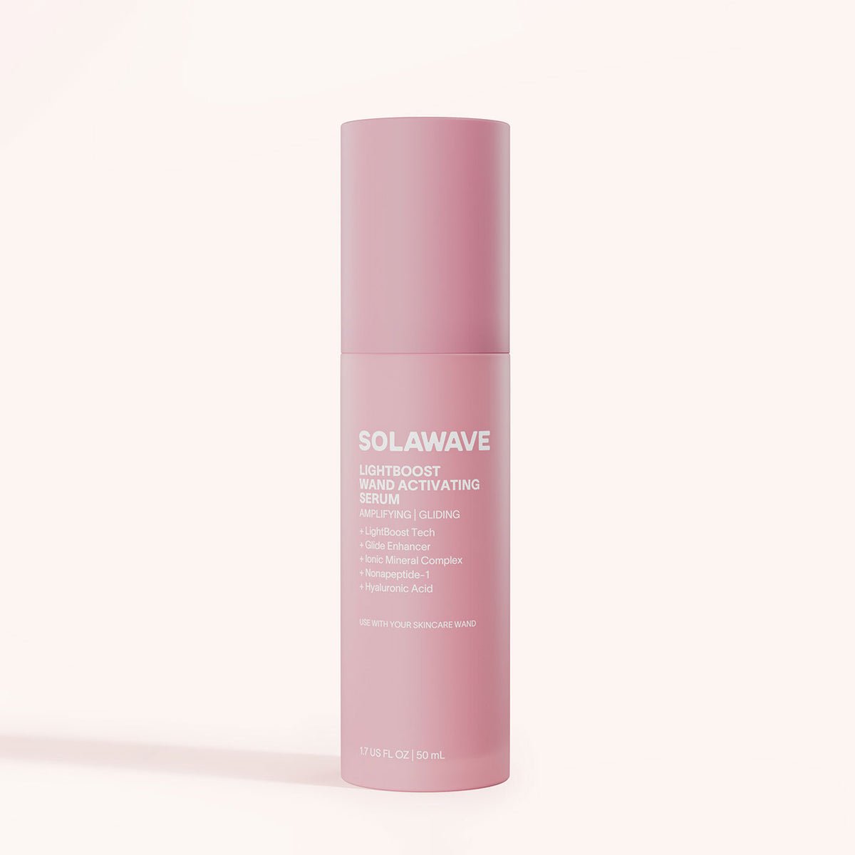 A pink cylindrical bottle of Solawave Light Therapy Boosting Wand Activating Serum, featuring white text and formulated to enhance light therapy with your skincare wand, stands upright against a light beige background.